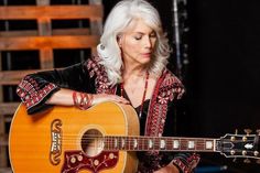 a woman holding an acoustic guitar in her hands