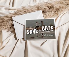 save the date cards are laying on top of a white bed sheet with a fur