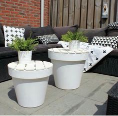 two white planters sitting next to each other on top of a cement floor near a couch