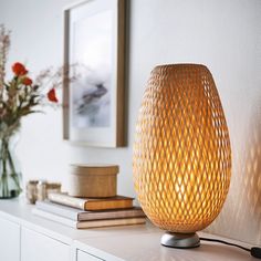 a lamp that is sitting on top of a table next to some books and flowers