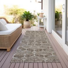 an outdoor area rug on a deck with furniture and potted plants in the background