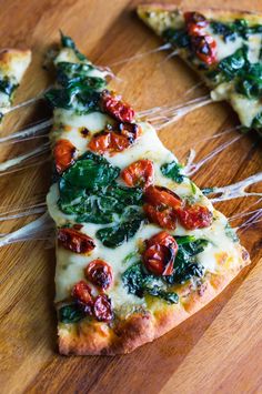 slices of pizza with spinach, tomatoes and cheese on a cutting board in the shape of a christmas tree