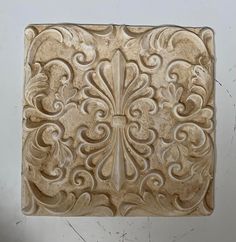 an intricately carved tile in the shape of a square with scrolls and flowers on it