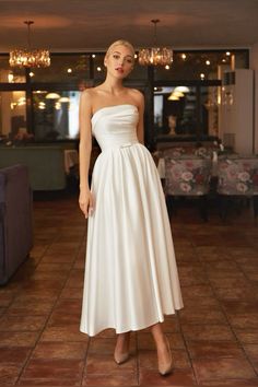 a woman in a white dress standing on a tile floor