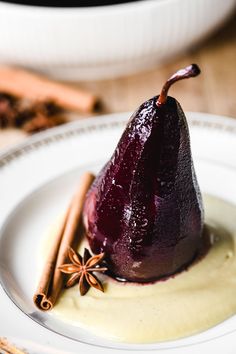 a plate topped with a pear covered in sauce and cinnamon stick garnished with star anise