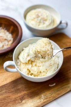 two bowls filled with mashed potatoes on top of a wooden cutting board