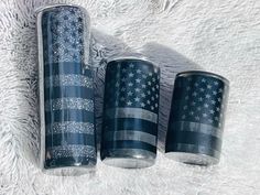 three blue tumbles with an american flag design on them sitting on a white blanket