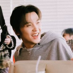 a young man sitting at a table smiling