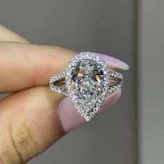 a woman's hand holding an engagement ring with a large diamond in the center