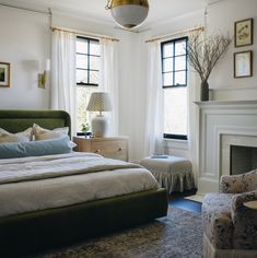 a bedroom with a bed, two chairs and a fire place in the middle of the room