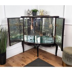 a round glass table with metal mesh coverings on the top and bottom, next to a potted plant