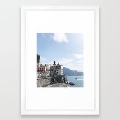 a white framed photograph with the sea in the background and buildings on the shore below