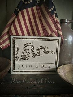 an american flag and some patriotic items on a shelf with a sign that says join or die the colonial tax