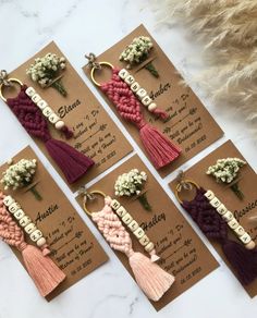 four key chains with tassels and flowers in them on top of a table