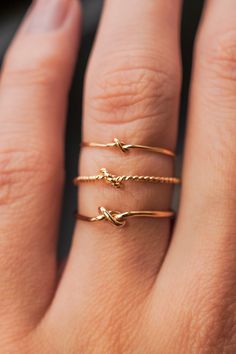 a woman's hand with three gold rings on her fingers and one is holding the other