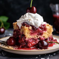 a slice of cherry pie on a plate with whipped cream and cherries