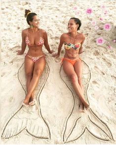 two women in bikinis sitting on the beach