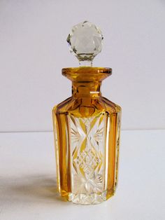 an empty glass bottle sitting on top of a white table next to a small crystal object