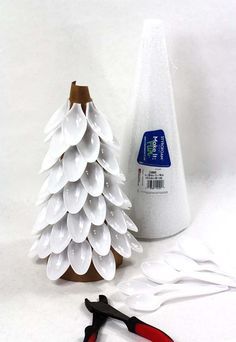 a plastic christmas tree next to pliers and glue on a white background with scissors