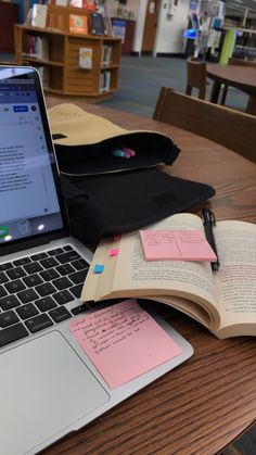 an open laptop computer sitting on top of a wooden table next to a notebook and pen