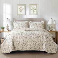 a bed with white sheets and pillows in a room next to two pictures on the wall