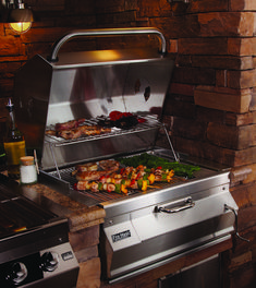 an outdoor grill with food cooking on it's burners and side burners