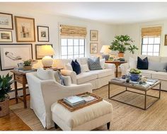 a living room filled with white furniture and lots of windows covered in shades of blue