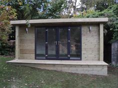 a small wooden building in the middle of a yard with windows and doors on each side