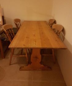 a wooden table with chairs around it in a room that has white walls and tile flooring