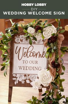 a welcome sign is decorated with flowers and greenery for a rustic wedding or reception