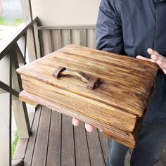 a man holding up a wooden box on a porch