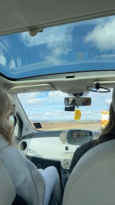 two women sitting in the back seat of a car looking out at an open field