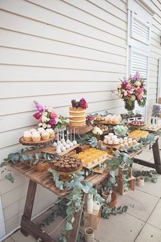 a table with cakes and cupcakes on it in front of a white house