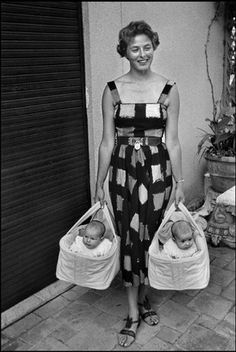 an old photo of a woman holding two babies