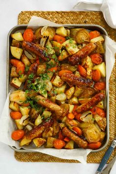 a tray filled with meat and vegetables on top of a table next to a fork