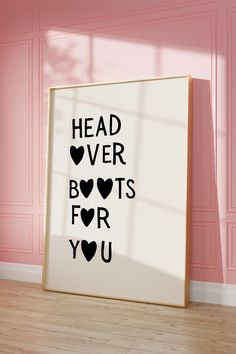 a framed poster with the words head over boots for you on it in front of a pink wall