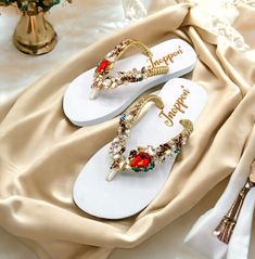 Description The beautiful rhinestone and customizable Flip Flops for the beach brides, bridesmaids, vacation, honeymoon or any occasion you desire to look gorgeous. Perfect in any outfit! Being unique and stunning on design, these flip flops must be your must-have item! The sandal is anti-slip, comfortable and durable as it is made from high quality rubber from the South of Thailand, where is famous for the best rubber tree. Moreover, the crystals are decorated on the sandal with effective adhesive glue and knitting threads by hand stitching. Don't worry when you walk on the beach or use it in the rainy season. For anyone who loves a real handmade product, don't miss it out! Product Description: - Thailand High-Quality Rubber Sole - Luxury Crystals/Rhinestones  - High-quality PU gold threa Summer Wedding Shoes With Rhinestones And Round Toe, Summer Wedding Shoes With Rhinestones, Gold Sandals For Summer Beach Wedding, Embellished Sandals For Beach Party, Embellished Sandals For Beach Season Parties, Gold Rhinestone Flip Flops For Vacation, Elegant Embellished Flip Flops For Vacation, White Flip Flops For Beach Season Parties, Elegant Gold Flip Flops For The Beach