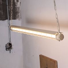 a light fixture hanging from the ceiling in a room with peeling paint on the walls