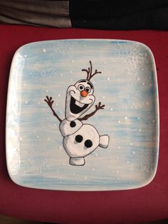 a plate with a cartoon character painted on it's side and snowflakes in the background