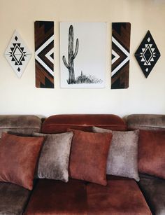 the couch is covered with many pillows in front of three paintings