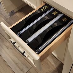 an open drawer with two knives in it on the floor next to a counter top