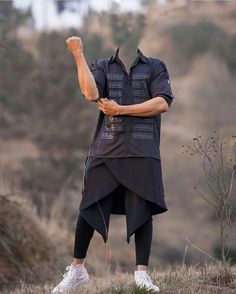 a man standing on top of a hill with his hands in the air while wearing white sneakers