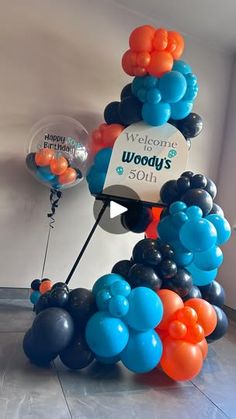 balloons are stacked on top of each other in the shape of a tower that reads welcome to woody's 50th