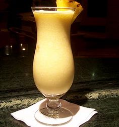 a tall glass filled with liquid sitting on top of a table next to a napkin