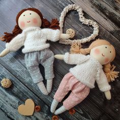 two dolls laying next to each other on top of a wooden floor with hearts and buttons