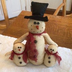 a stuffed snowman and two small dolls on a table