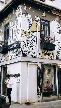 a man standing in front of a building that has graffiti on the side of it