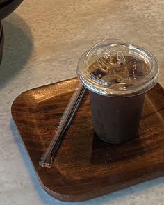 a drink in a plastic cup sitting on top of a wooden tray