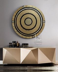 a modern sideboard in gold and black with an abstract design on the wall above it