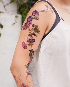 a woman's arm with flowers and vines tattooed on the back of her shoulder